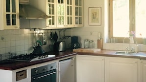 Cucina con mobili bianchi, piano cottura e lavastoviglie. Una finestra offre vista sul verde circostante.