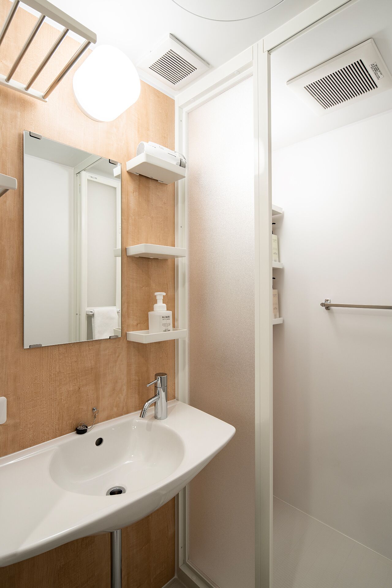A modern bathroom with a white sink, mirror, and shower.