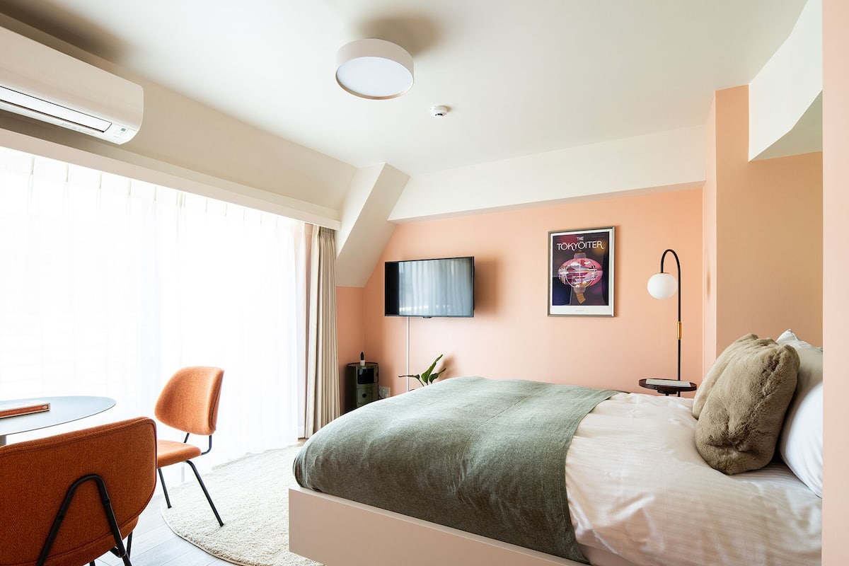 A modern hotel room with a bed, a TV, a desk, and a chair.