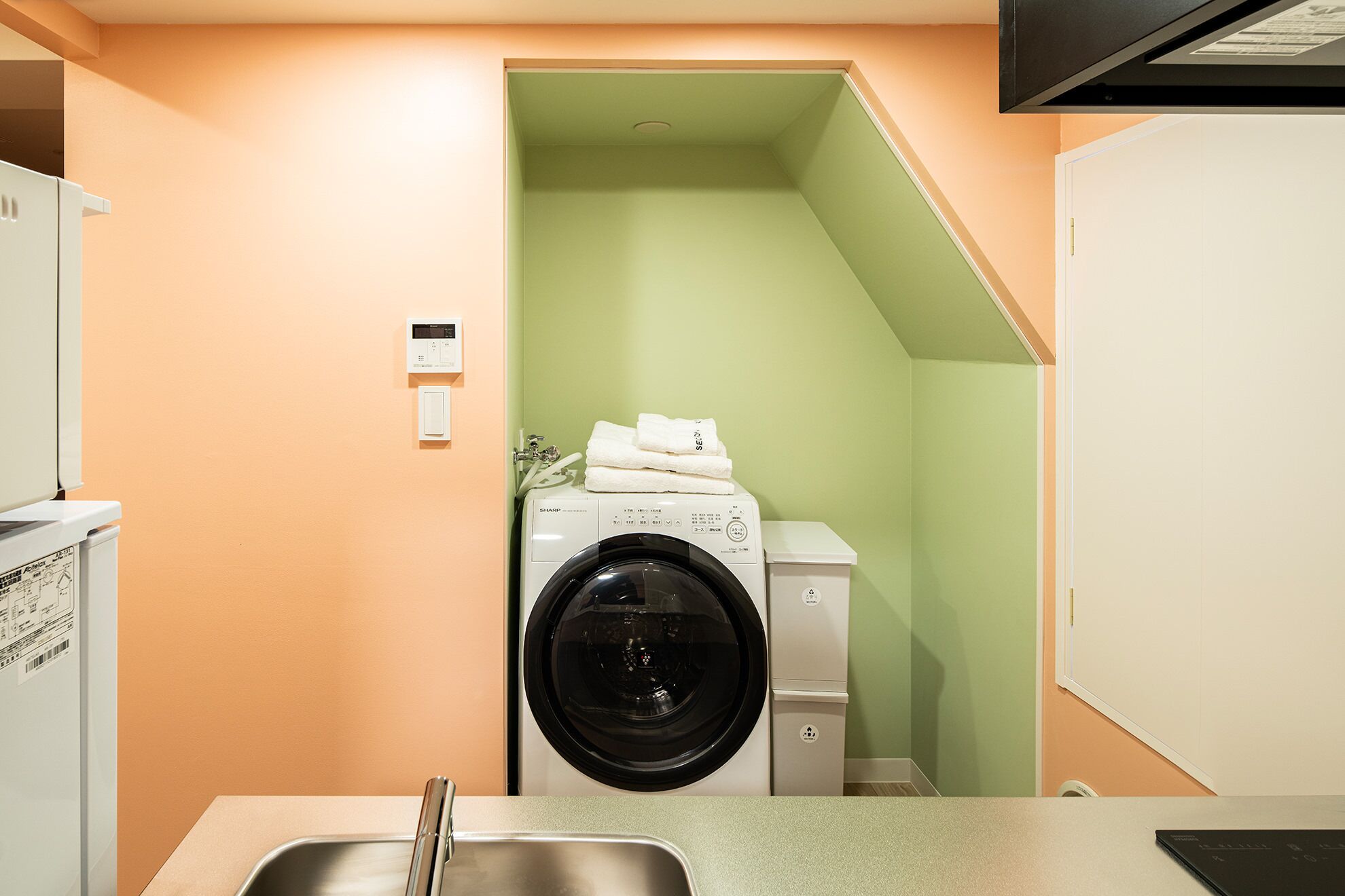 A compact laundry room with a washing machine, a dryer, and a sink.