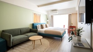 Une chambre d’hôtel moderne équipée d’un lit, d’un canapé, d’une petite table ronde et d’un téléviseur.