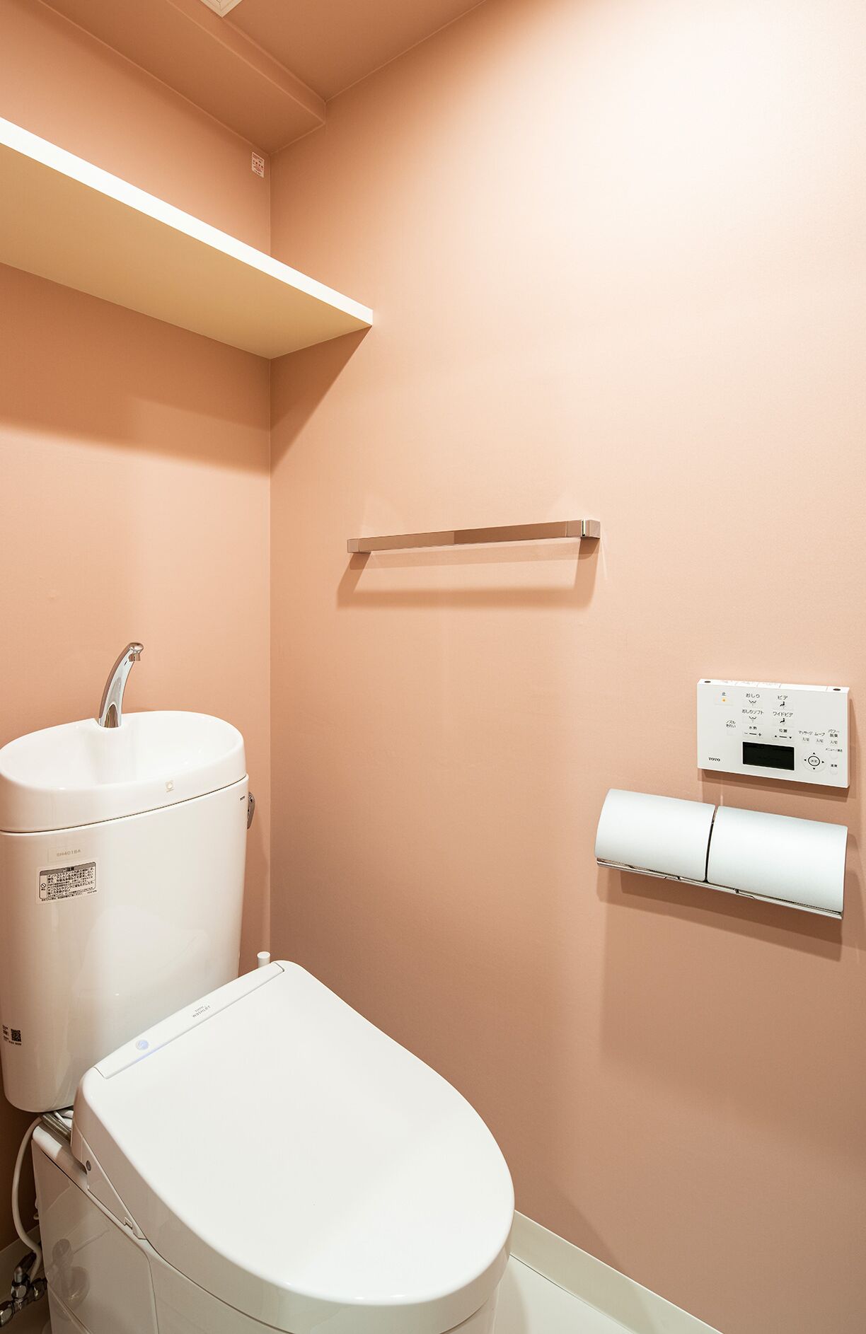A bathroom with a toilet, a sink, and a toilet paper holder.