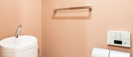 A bathroom with a toilet, a sink, and a toilet paper holder.