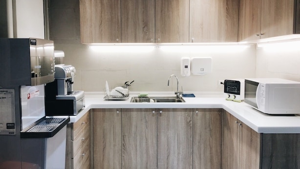 A modern kitchen with wooden cabinets, a built-in coffee machine, a microwave, and a sink with a dish rack. - Gents House - Hostel (Taipei)