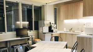 A modern kitchen with a dining area, equipped with a coffee machine, microwave, and a sink. - Gents House - Hostel (Taipei)