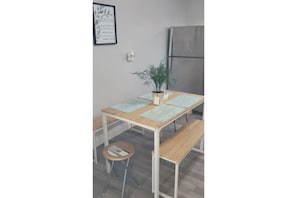 A small kitchenette with a wooden table, a bench, and a potted plant.