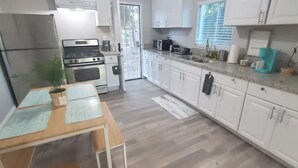Une cuisine moderne avec des meubles blancs, un réfrigérateur en acier inoxydable, une cuisinière et un four à micro-ondes.