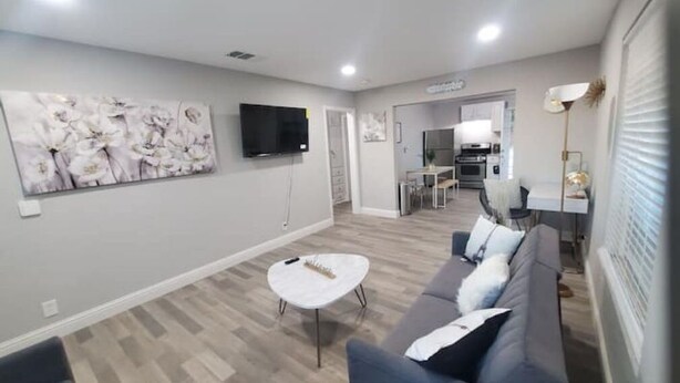 Un salon moderne avec un canapé gris, une table basse blanche et un téléviseur à écran plat fixé au mur.