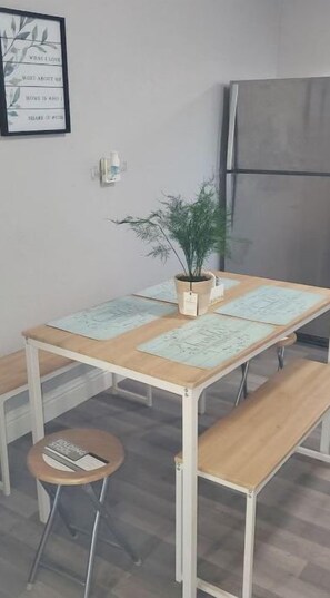Una pequeña kitchenette con una mesa de madera, un banco y una planta en maceta.