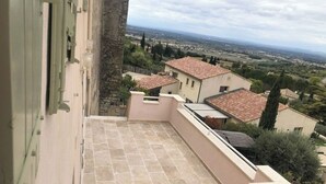 Un balcón con suelo de piedra y vistas a un pueblo con casas de tejados rojos.