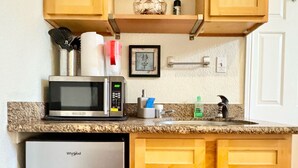 Una cucina compatta con mobili in legno, un forno a microonde, un frigorifero e un lavello.