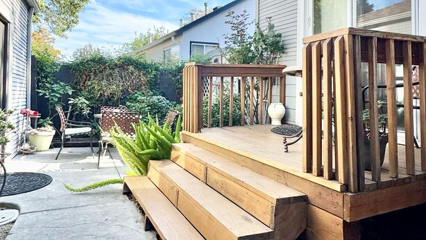 Un terrazza in legno con gradini che conducono a una casa con una finestra e una porta.