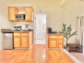 Compact kitchen with a refrigerator, microwave, and coffee maker, offering a convenient space for meal preparation.