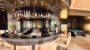 Eine Bar mit einer Poolbillardtisch, Barhocker und einer Auswahl an Flaschen im Regal.