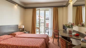 A hotel room with two beds, a desk, a chair, a mirror, and a view of the outside.