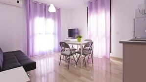 A modern living room with a sofa, a dining table with chairs, a TV, and purple curtains.