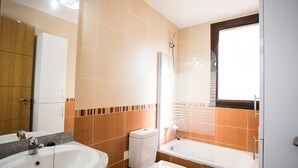 A bathroom with a sink, toilet, bathtub, and a window.