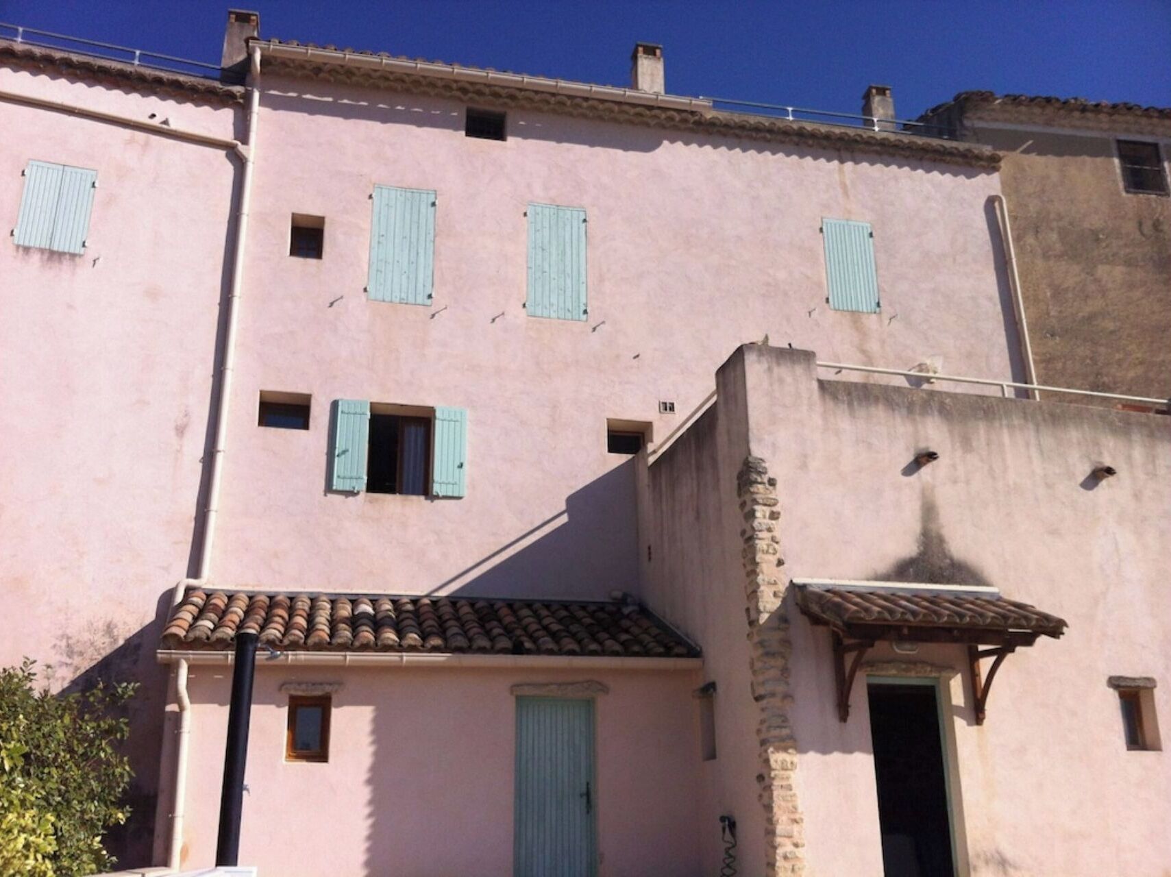 A pink building with multiple windows and a tiled roof.