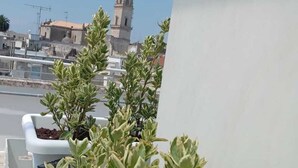 A balcony with potted plants and a view of a historic tower. - De Guidani Experience (Lecce)