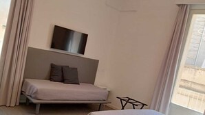 A modern bedroom with a bed, a TV, and a unique circular light fixture. - De Guidani Experience (Lecce)