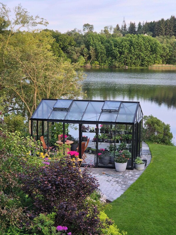 A glass greenhouse structure with potted plants and a seating area.