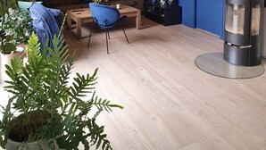 Un salon avec un canapé, une table basse, un fauteuil bleu, une cheminée et un téléviseur fixé au mur.