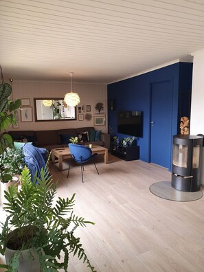 A living room with a sofa, a coffee table, a blue chair, a fireplace, and a TV on the wall.
