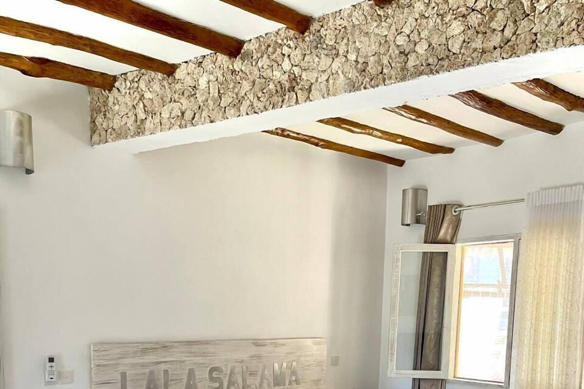 Quarto bem arrumado com cama, mesas de cabeceira e cabeceira decorativa.