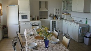 Une cuisine compacte avec des meubles blancs, une table à manger pour quatre personnes et un petit réfrigérateur.