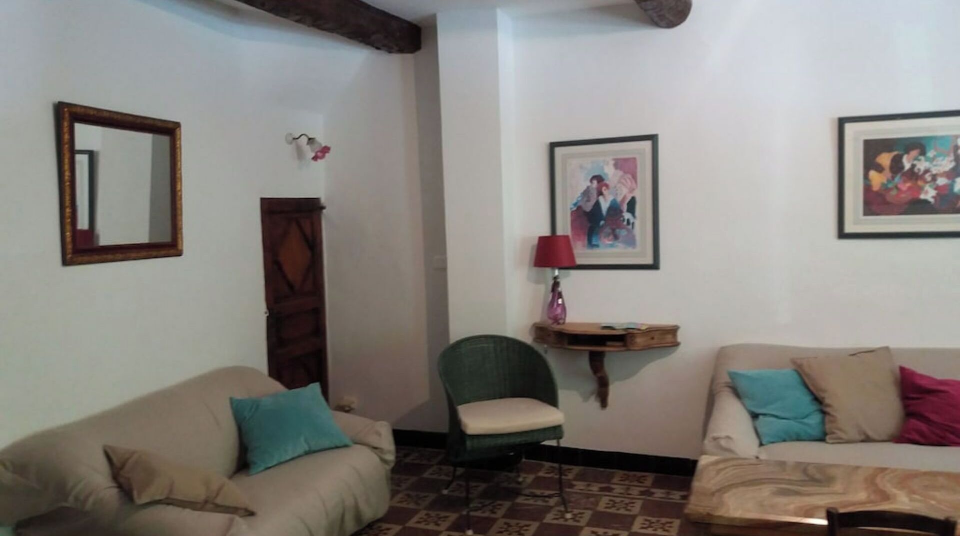 Een woonkamer met twee banken, een fauteuil, een houten kast en een wandplank met een lamp.