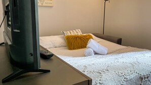 Una habitación de hotel con una cama, un control remoto, una manta y una almohada.