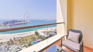 Een balkon met uitzicht op een strand, een reuzenrad en een stadsgezicht.