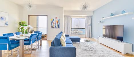 A modern living room with a dining area, a sofa, a TV, and a large window with a view of a Ferris wheel.