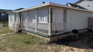 A single-story mobile home with a covered porch, a small front yard, and a barbecue grill. - Queen Anne's Revenge At The Beach 3 Bedroom Cottage by RedAwning (Kitty Hawk)