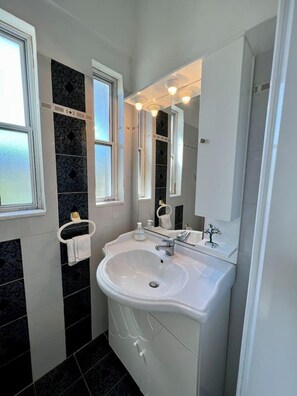 A modern bathroom with a white sink, a mirror, and a window.