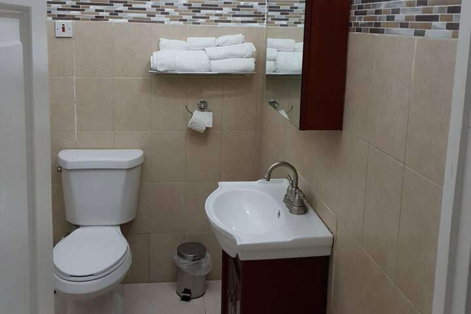 Un baño pequeño con inodoro, lavamanos y espejo.