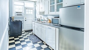 Une cuisine compacte avec des meubles blancs, un réfrigérateur en acier inoxydable, un four à micro-ondes et un petit évier.