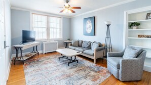 Un salon comprenant un canapé, un fauteuil, une table basse, un téléviseur et un ventilateur de plafond.