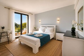 Un dormitorio con cama, mesitas de noche, un escritorio y vistas a la vegetación.