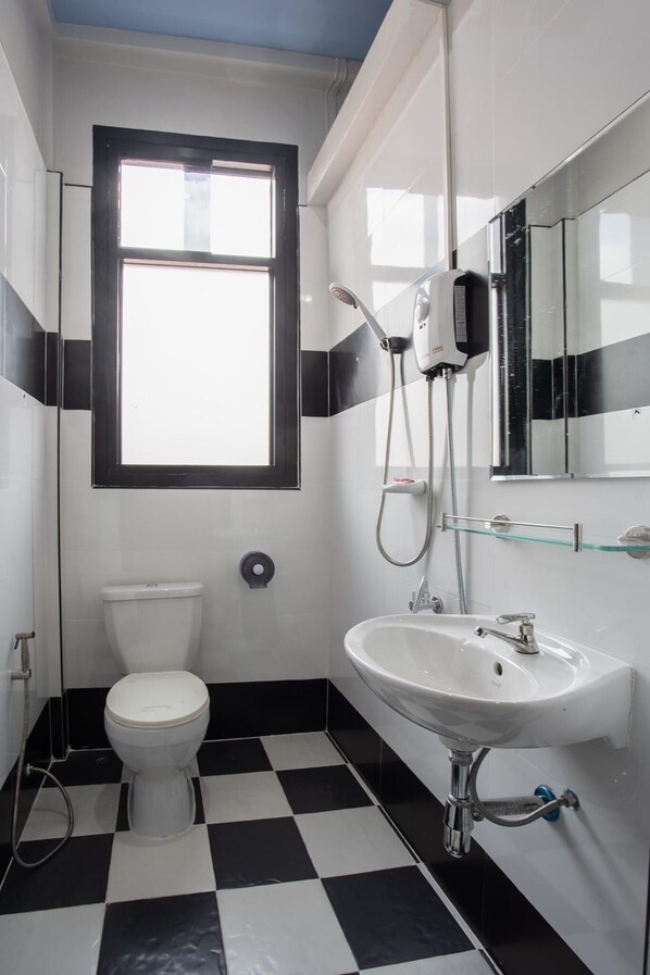 A bathroom with a toilet, a sink, a shower, and a window.