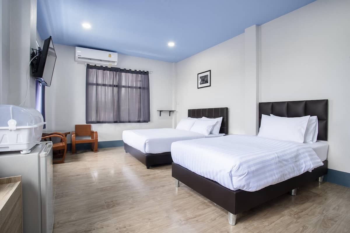 A hotel room with two beds, a TV, an air conditioner, and a wooden chair.