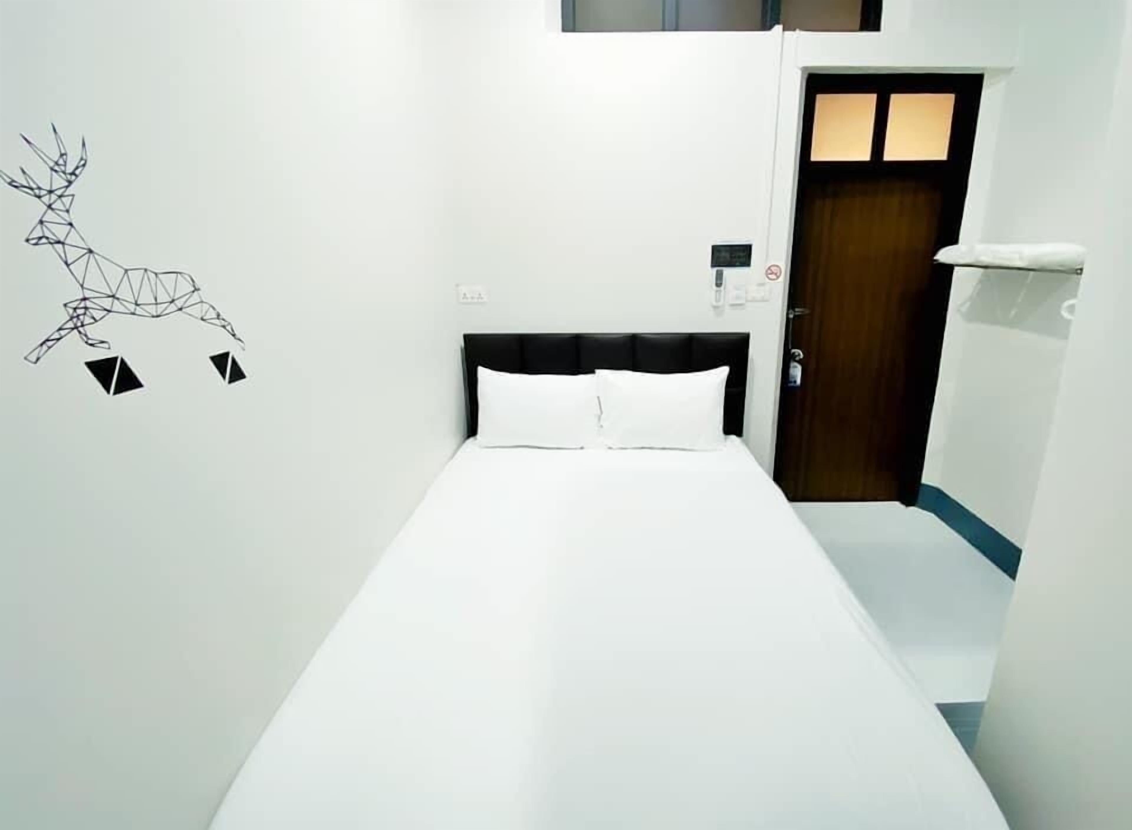 A hotel room with a bed, a door, and a wall decal of a deer.