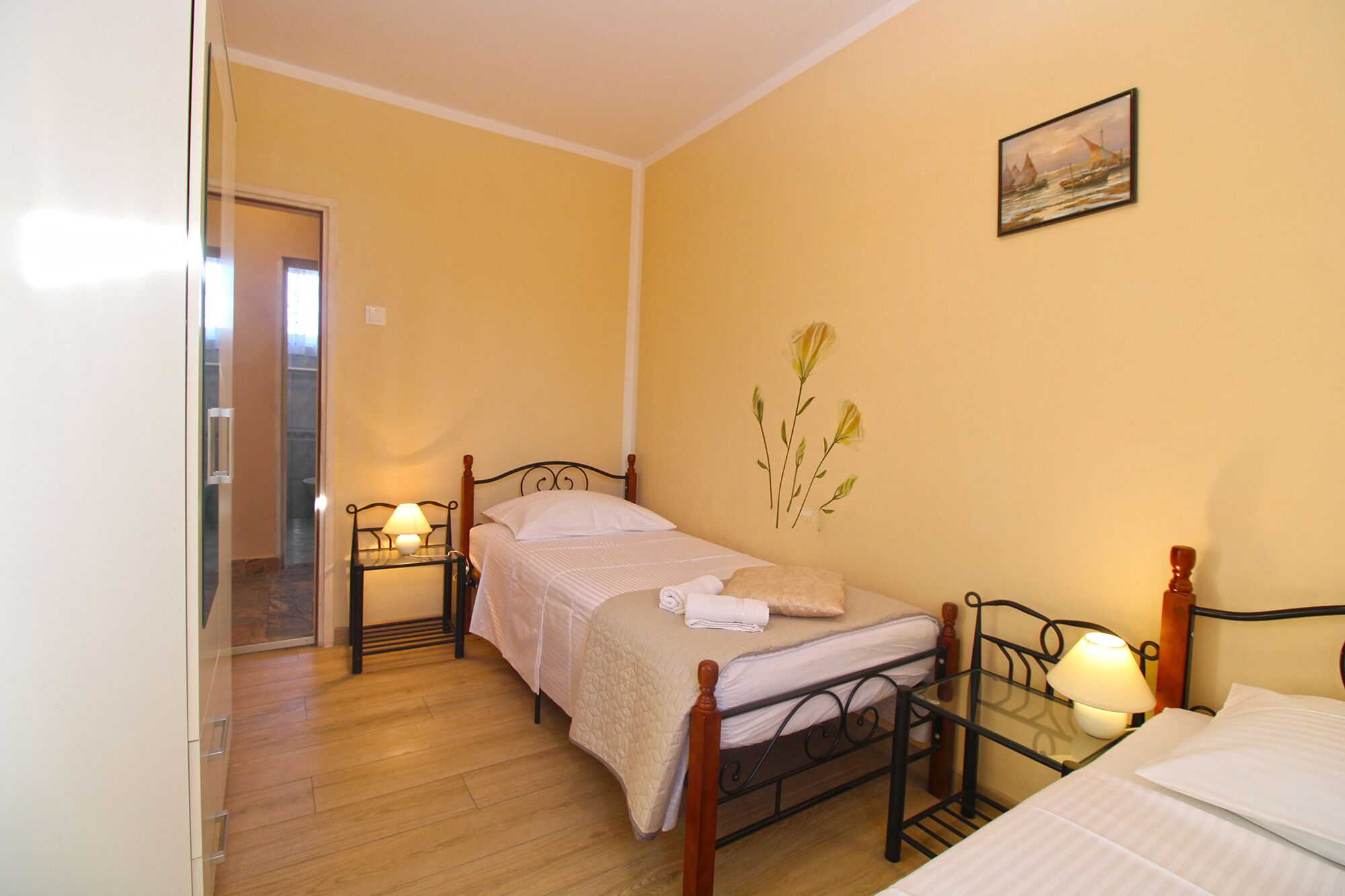 Une petite chambre confortable avec deux lits simples, un plancher en bois et un tableau accroché au mur.