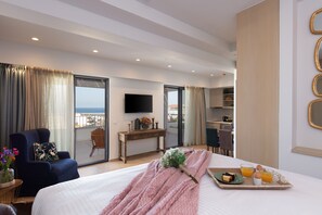 Quarto de hotel com cama, escrivaninha, cadeira, televisão e varanda com vista.