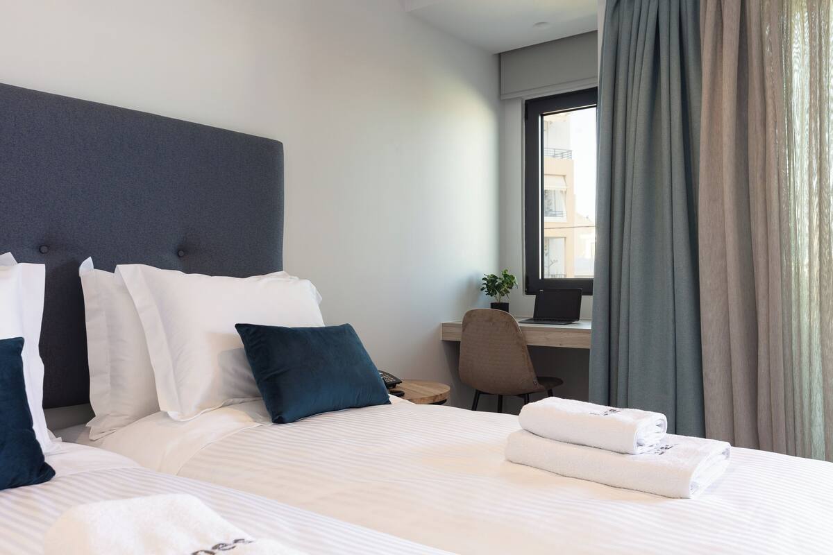 A hotel room with a large bed, a desk, and a window with curtains.