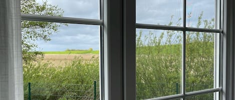 A window with a view of a field and a fence.