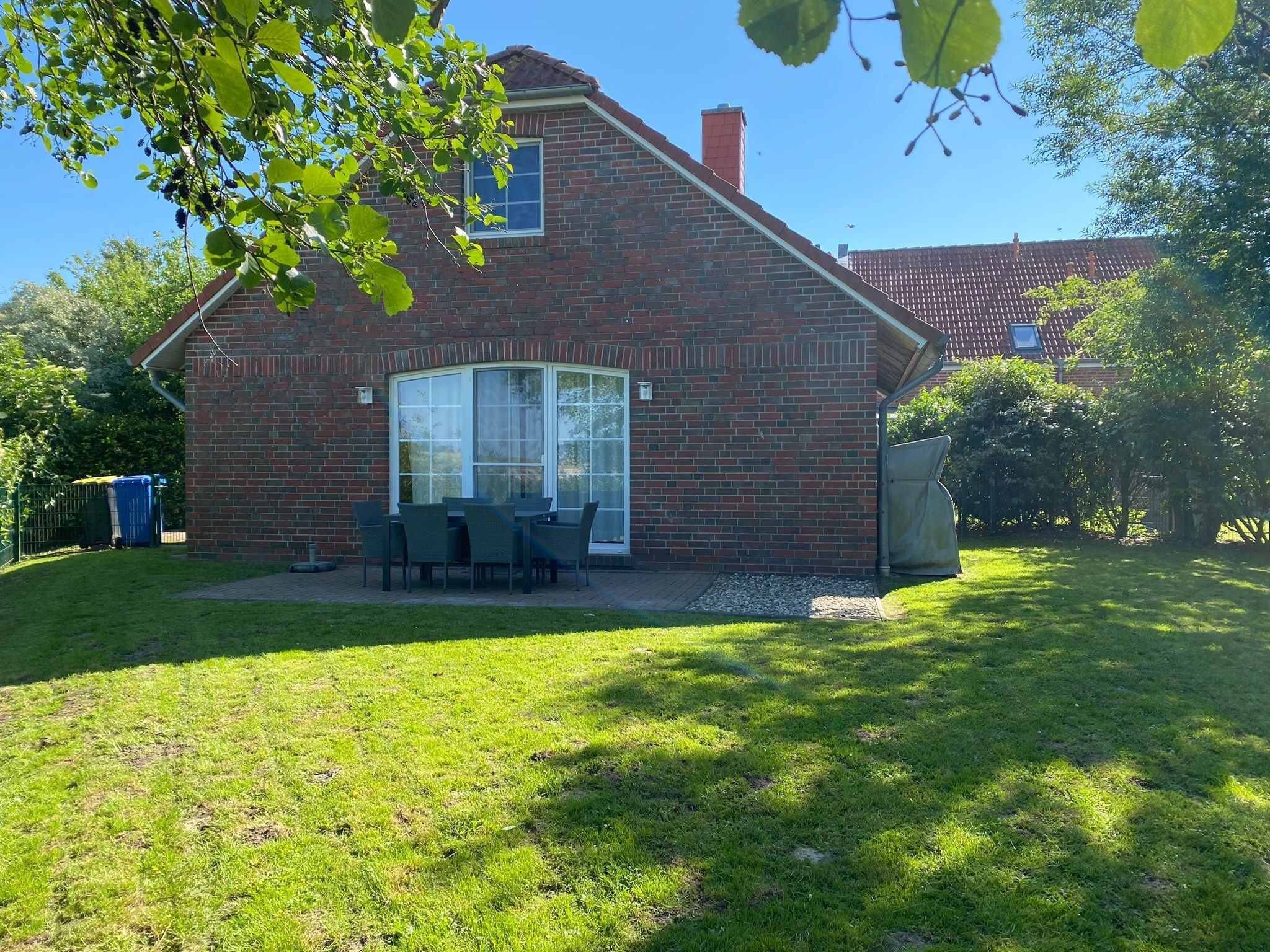 Ein Ziegelhaus mit Terrasse, großem Fenster und kleinem Garten.