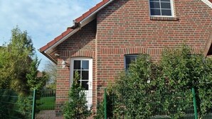 A two-story brick house with a gabled roof, a front door, and two windows. - Beautiful vacation home in a cul-de-sac location with unobstructed views (Greetsiel)