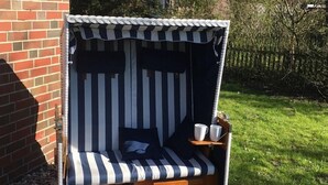 A small, enclosed outdoor seating area with striped cushions and a wooden bench. - Beautiful vacation home in a cul-de-sac location with unobstructed views (Greetsiel)