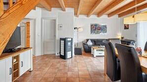 A modern living room with a wooden staircase, a flat-screen TV, a sofa, and a coffee table. - Wunderschönes Ferienhaus mit Eigenem Tretboot (Greetsiel)